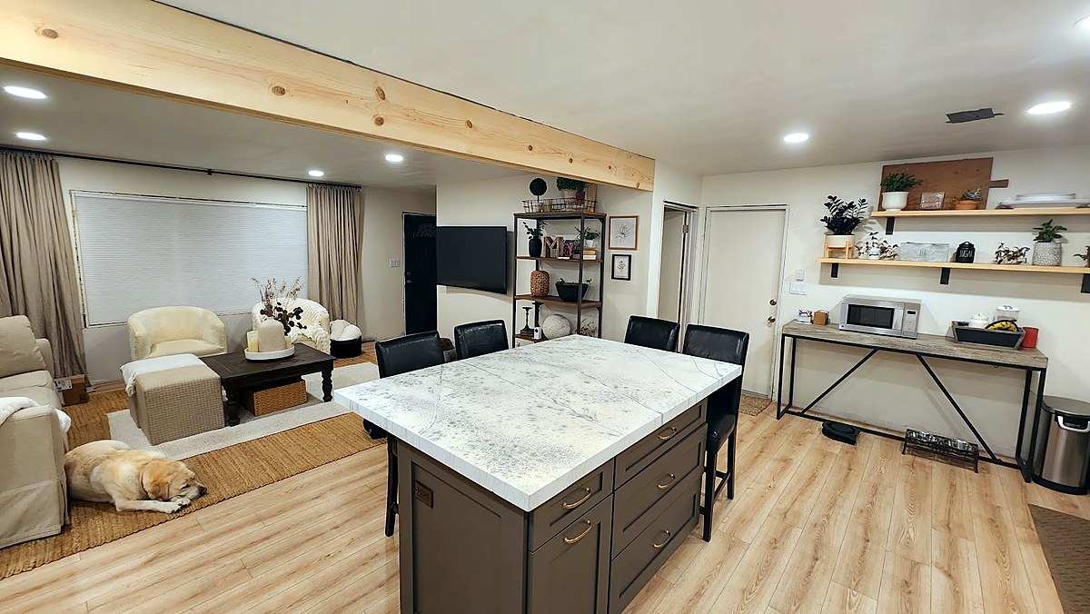 Roland living room after renovation — open concept with exposed wood beam